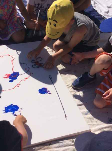 children drawing on a large piece of paper outdoors